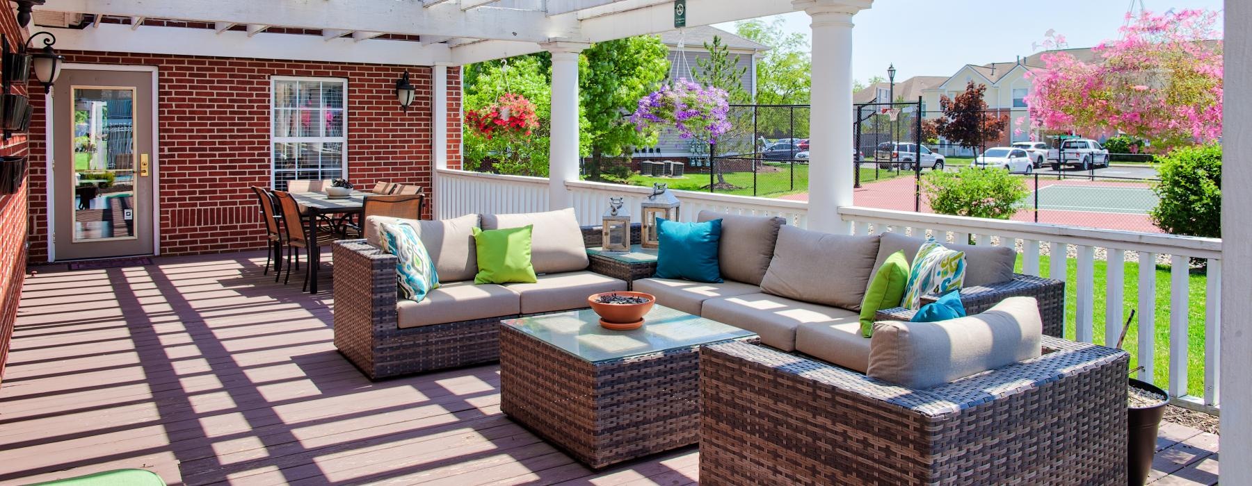 a patio with a couch and a table with a lamp and a building in the background