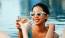 a woman in a pool holding a drink and a glass