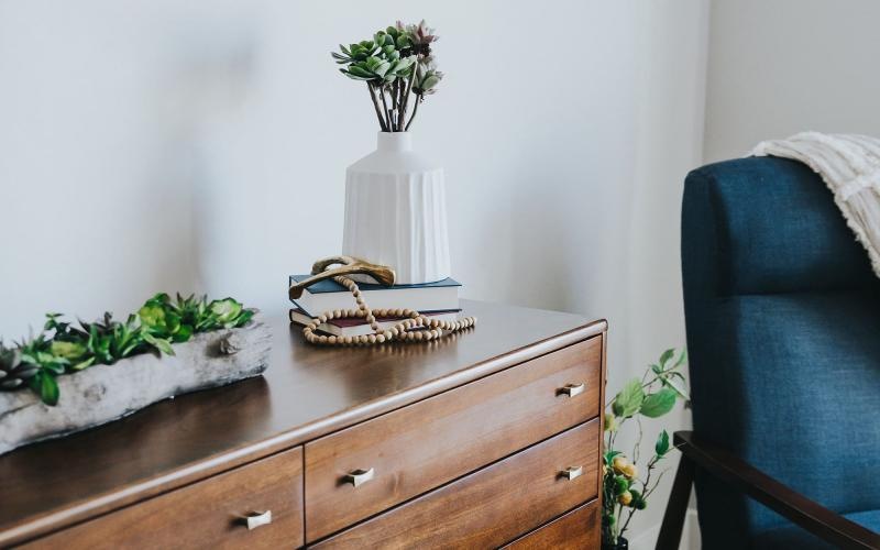 a dresser with a vase of plants on top